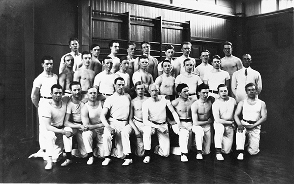 Grupp manliga gymnaster i vita gymnastikkläder.