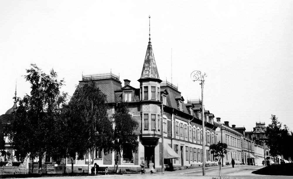 Hus med spetsigt hörntorn på stadsgata.